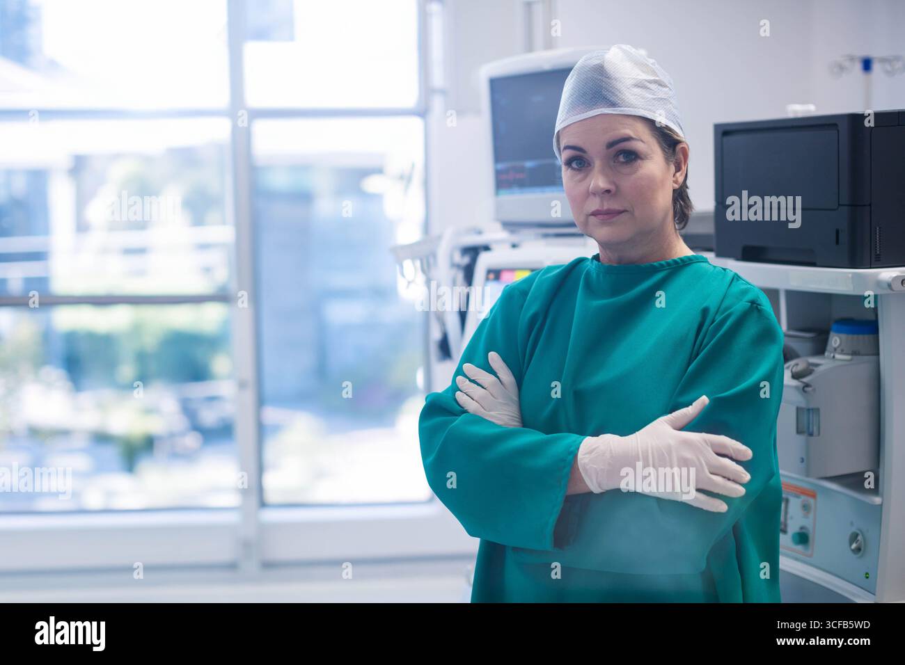 Chirurgien femme senior portant des gommages debout près de la machine d'anesthésie dans la salle chirurgicale, espace de copie Banque D'Images