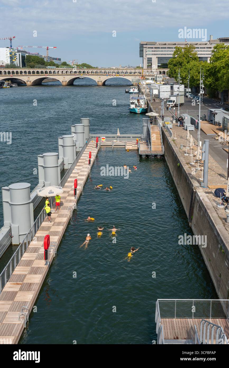 Les gens nagent dans la Seine à Bercy, le 12ème arrondissement de Paris. En arrière-plan le bâtiment du ministère de l'économie, des Finances Banque D'Images