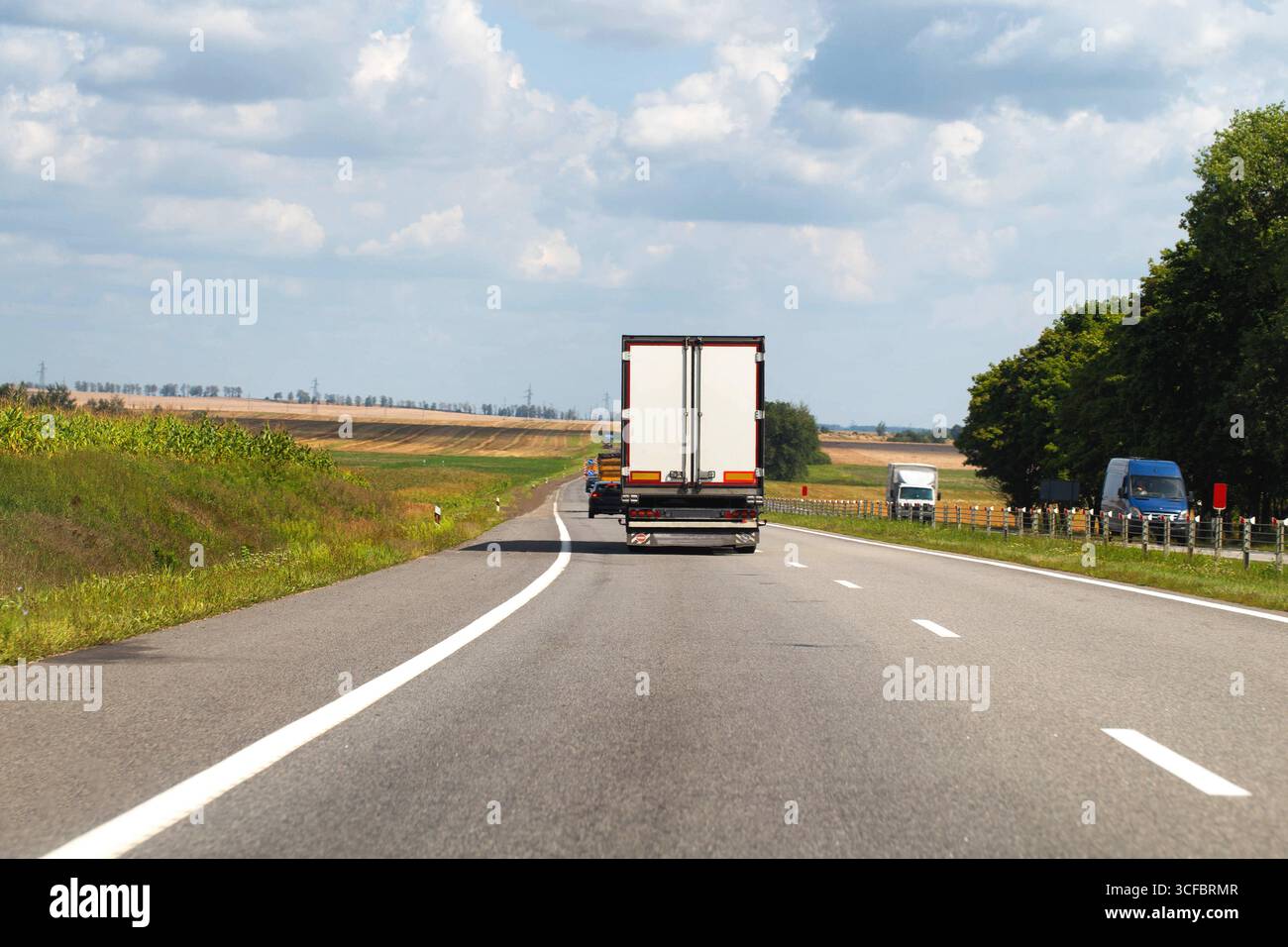 Un camion avec une semi-remorque livre la cargaison le long de l'autoroute au marché. Service de livraison d'une boutique en ligne à l'acheteur. Banque D'Images