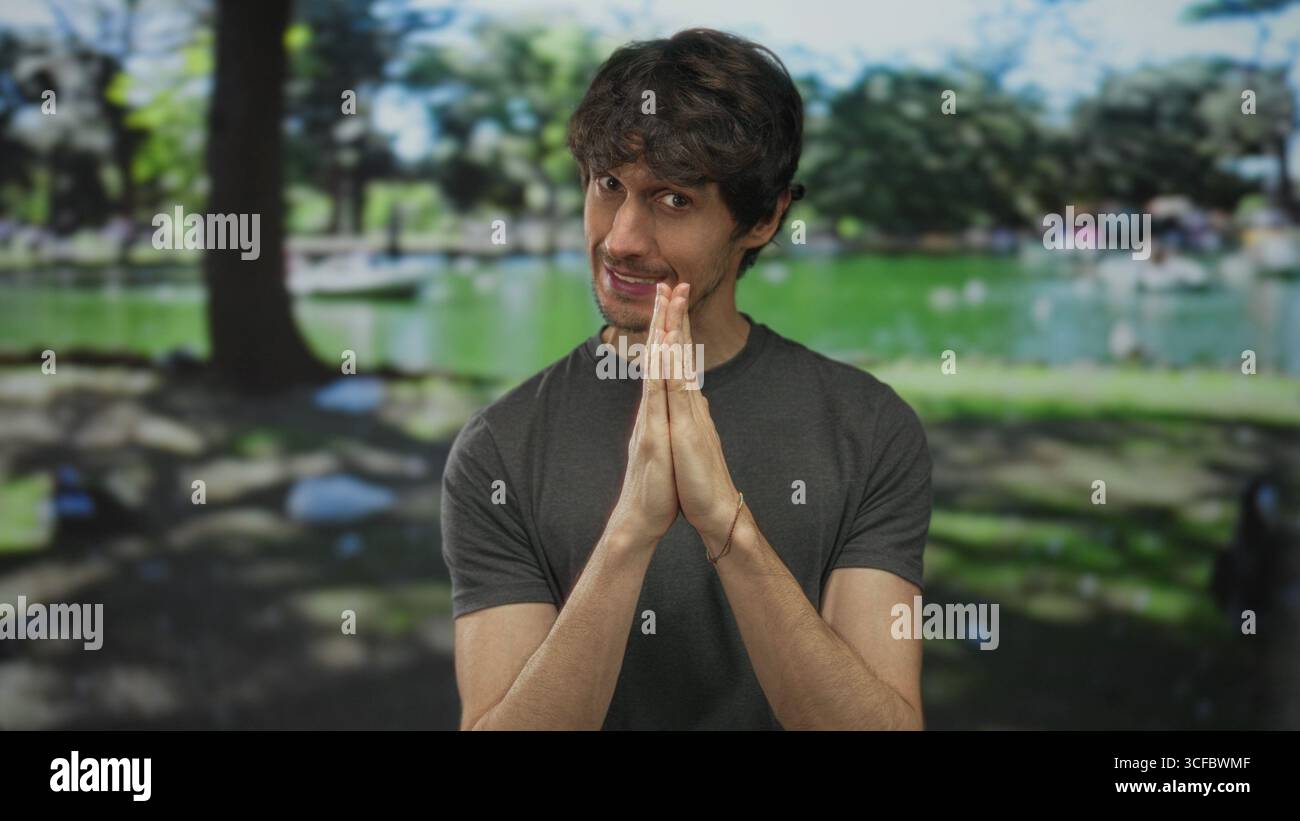 Homme pressant les mains ensemble dans un geste de prière sous la canopée verte dans la forêt ; espoir réflexion patience. Banque D'Images