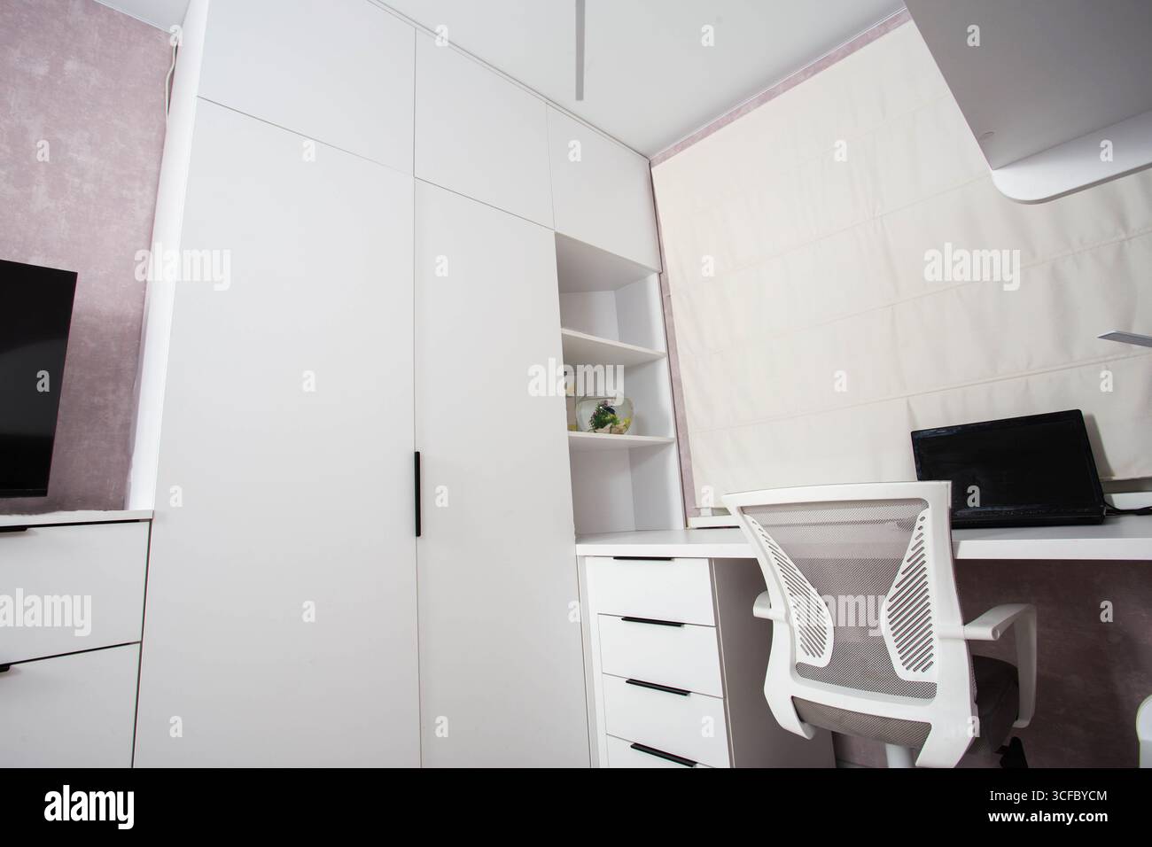 Placard blanc avec bureau informatique, chaise d'ordinateur et ordinateur portable dans la chambre. Banque D'Images