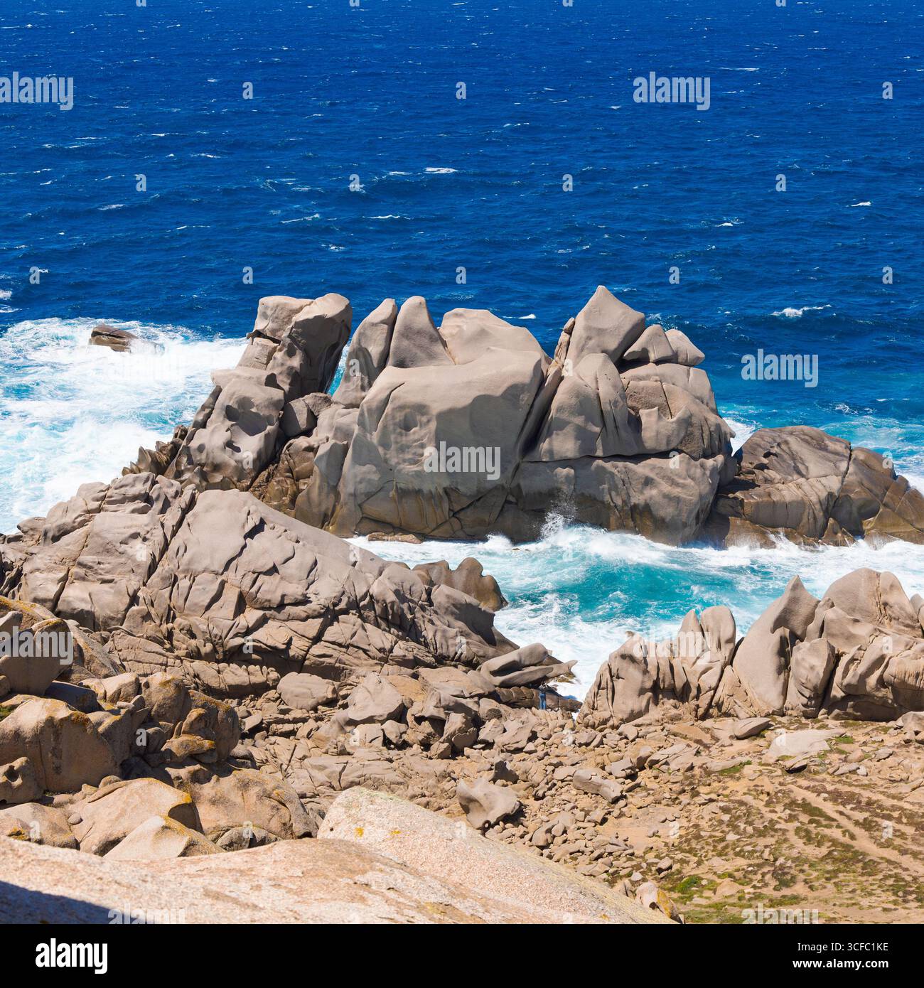 Roches granitiques massives à Capo Testa, Sardaigne, façonnées par le vent et les vagues, entourées par la mer bleu profond et les vagues blanches écrasantes. Banque D'Images