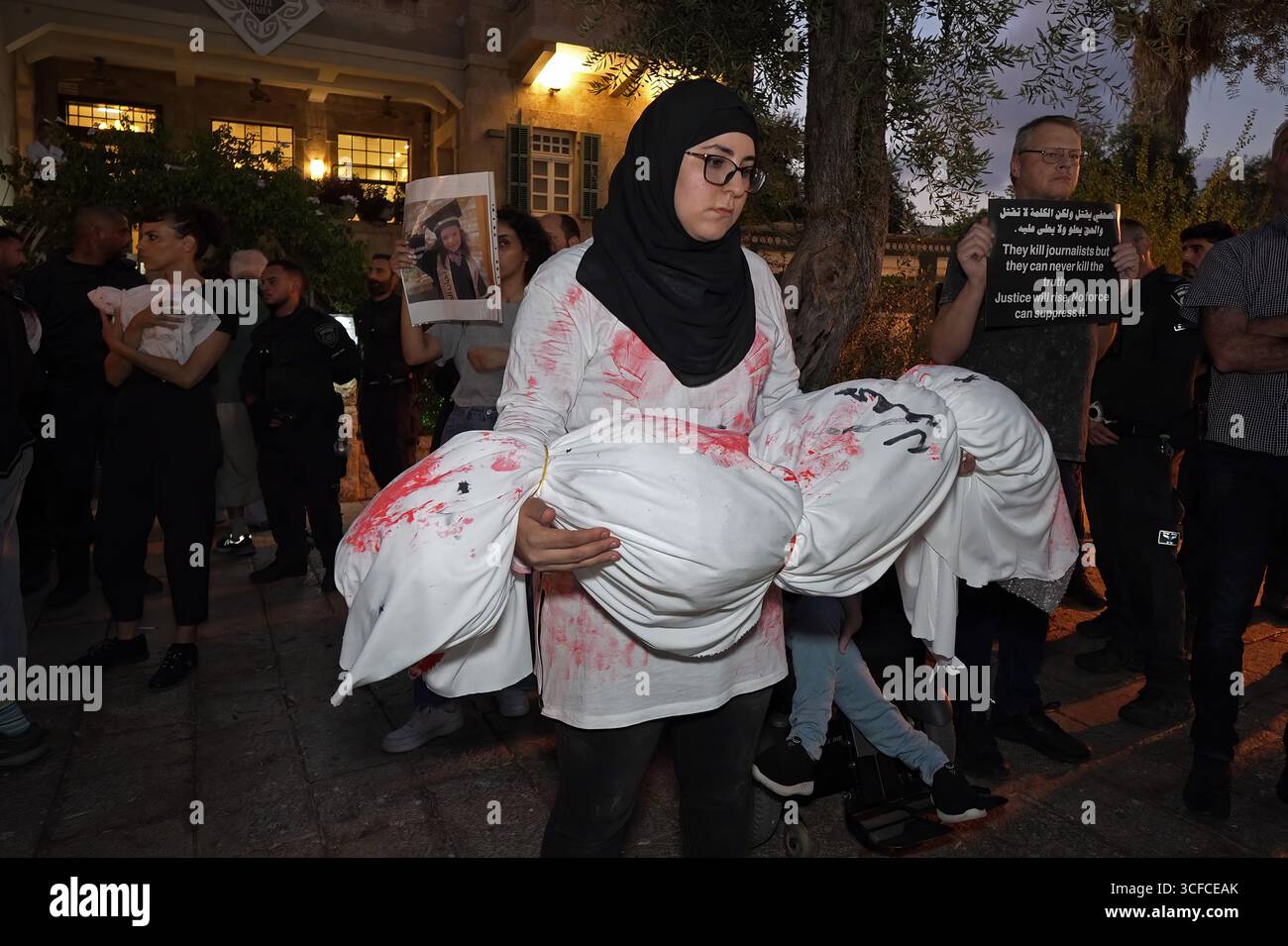 HAÏFA, ISRAËL - 21 AOÛT : les manifestants tiennent des colis enveloppés dans des enveloppes, symbolisant les corps d'enfants palestiniens tandis que d'autres manifestants arabes israéliens et militants pour la paix tiennent des pancartes condamnant la guerre, aux côtés de photos d'enfants palestiniens et de journalistes tués par l'armée israélienne à Gaza lors d'une manifestation contre la guerre israélienne dans la bande de Gaza le 21 août 2025 à Haïfa, Israël. Banque D'Images