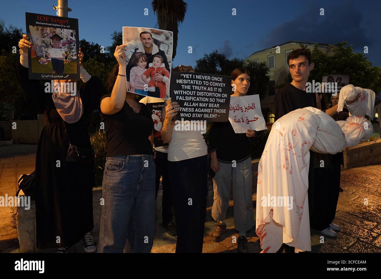 HAÏFA, ISRAËL - 21 AOÛT : les manifestants tiennent des colis enveloppés dans des enveloppes, symbolisant les corps d'enfants palestiniens tandis que d'autres manifestants arabes israéliens et militants pour la paix tiennent des pancartes condamnant la guerre, aux côtés de photos d'enfants palestiniens et de journalistes tués par l'armée israélienne à Gaza lors d'une manifestation contre la guerre israélienne dans la bande de Gaza le 21 août 2025 à Haïfa, Israël. Banque D'Images