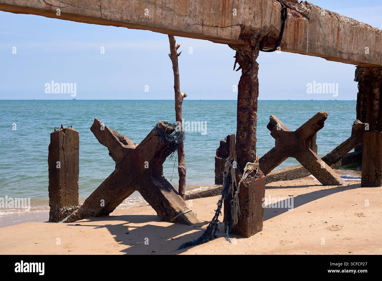 Vieux quai en béton détérioré ou quai reste sur la plage tropicale. Structure maritime rustique avec corde et béton altéré sur fond d'océan. P Banque D'Images
