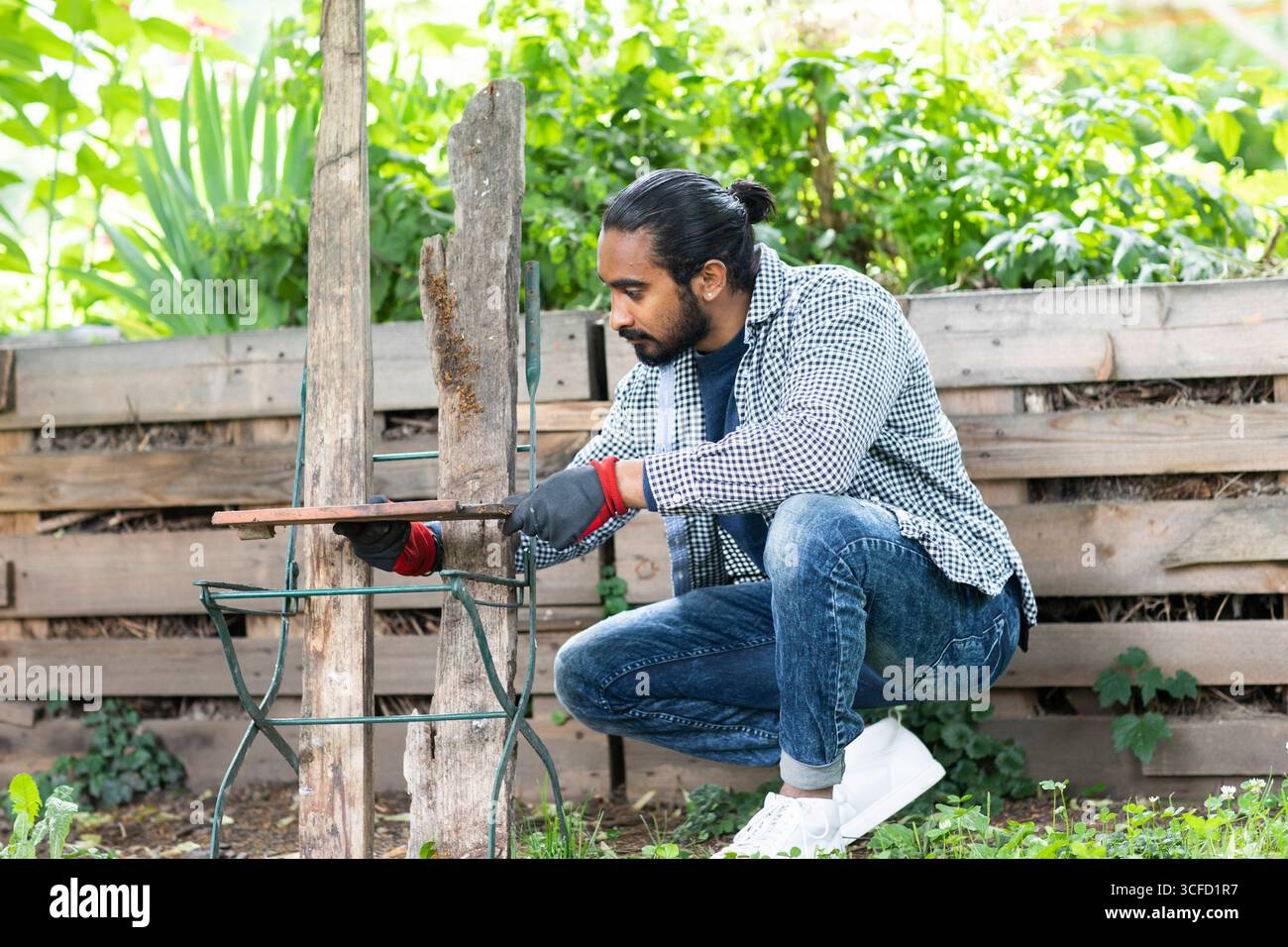 Homme en tenue décontractée effectuant le travail du bois en plein air dans un cadre de jardin luxuriant. Allemagne Banque D'Images
