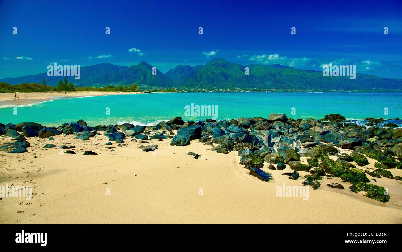 Une plage sereine avec des eaux turquoises et des montagnes vertes lointaines sous un ciel bleu clair. Kanaha Beach Park, West Maui Mountains, Kite Beach, Kahului, Hawaï Banque D'Images