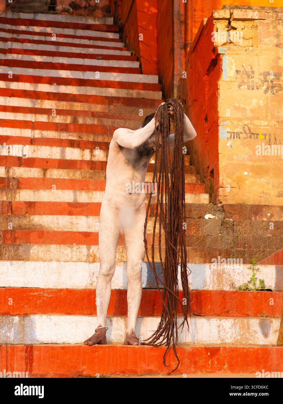 Naga Sadhu (ascète hindou) couvert de frêne sacré (Bhasma) arrangeant ses dreadlocks sur les Ghats de Varanasi. Banque D'Images