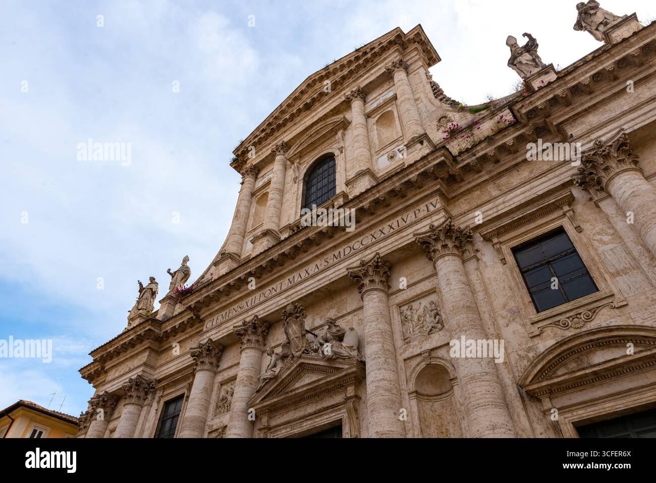 Façade baroque d'une église historique de Rome avec statues ornées, colonnes et inscription latine Banque D'Images