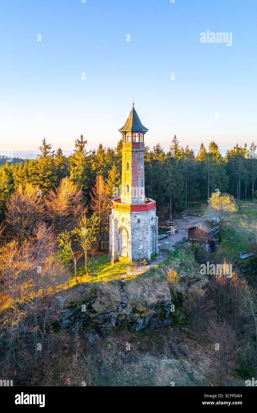 La tour de guet Stepanka se dresse contre un ciel de printemps clair à Korenov, entouré d'une végétation luxuriante. La lumière du soleil illumine la tour, soulignant sa beauté architecturale. Banque D'Images
