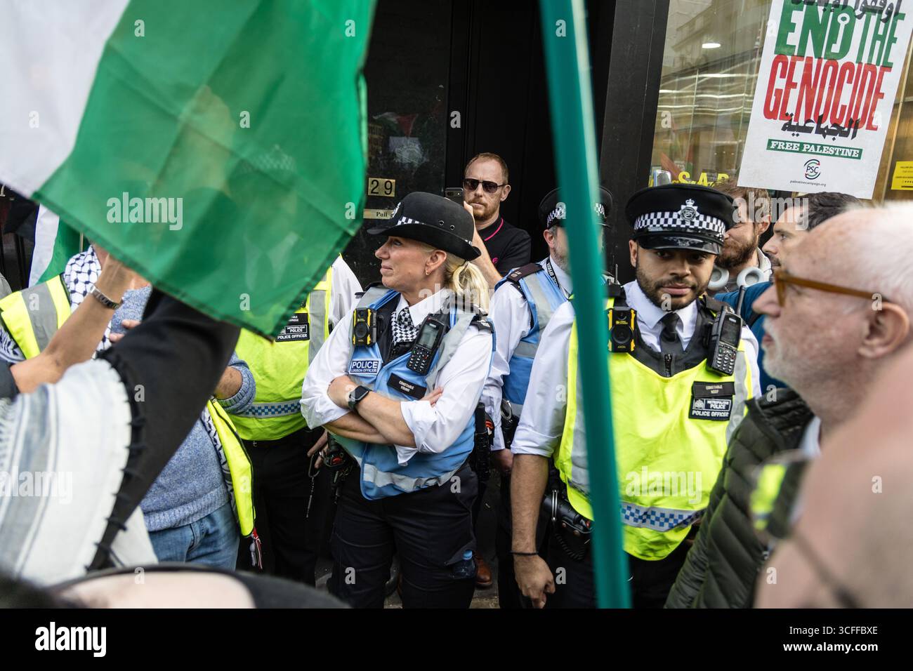 LONDRES, Royaume-Uni - 22 août 2025 : des policiers tiennent un partisan israélien dans une porte alors que des manifestants pro-palestiniens entourent la zone lors d'une manifestation devant l'ambassade israélienne. L'action, menée par la campagne de solidarité palestinienne, a exigé un cessez-le-feu et une intervention internationale pour arrêter l'assaut contre Gaza. Banque D'Images