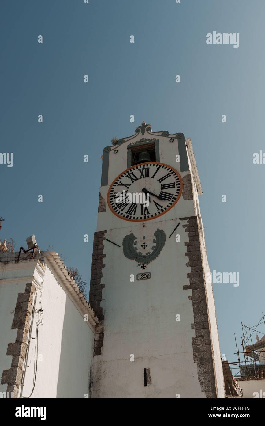 Faro, Algarve, Portugal – 2025.07.02 – gros plan d’une tour historique de l’horloge de la cathédrale datant de 1809 avec des chiffres romains et une cloche sur un ciel bleu clair. Banque D'Images