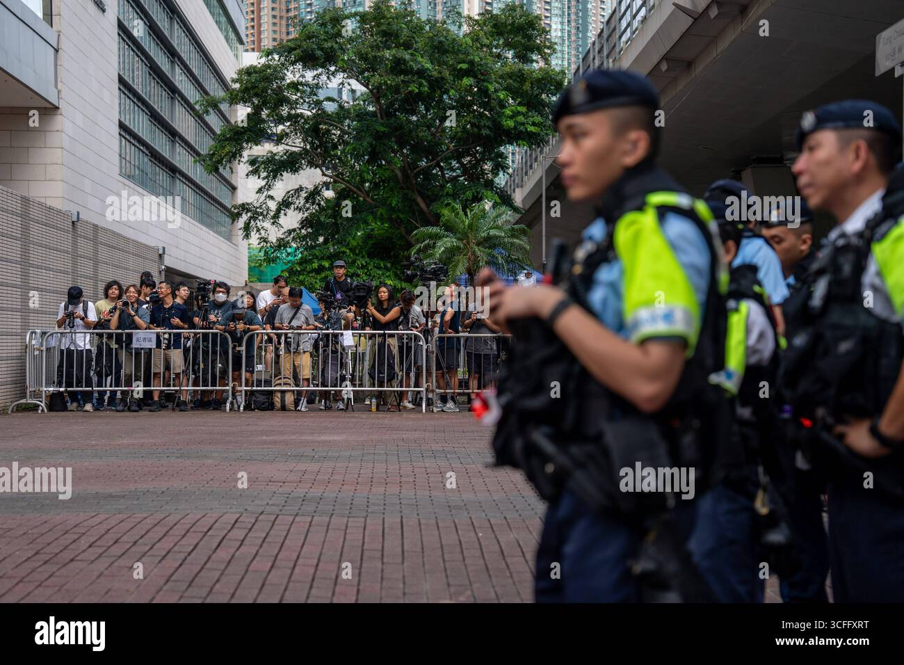 Défend à Hong Kong 47 affaire Démocrates appel condamnation et condamnation des agents de police debout la garde aux côtés de journalistes dans une zone de presse désignée par la police devant les tribunaux de première instance de West Kowloon le 14 juillet 2025 à Hong Kong. Douze militants de Hong Kong qui, condamnés et condamnés dans l'affaire historique des démocrates de 47, ont fait appel de leurs condamnations pour subversion et de leurs peines de prison devant un tribunal de Hong Kong aujourd'hui, ils ont été arrêtés et accusés de complot en vue de commettre des actes subversifs au début de 2021 pour avoir participé aux élections primaires du camp pro-démocratie. Banque D'Images