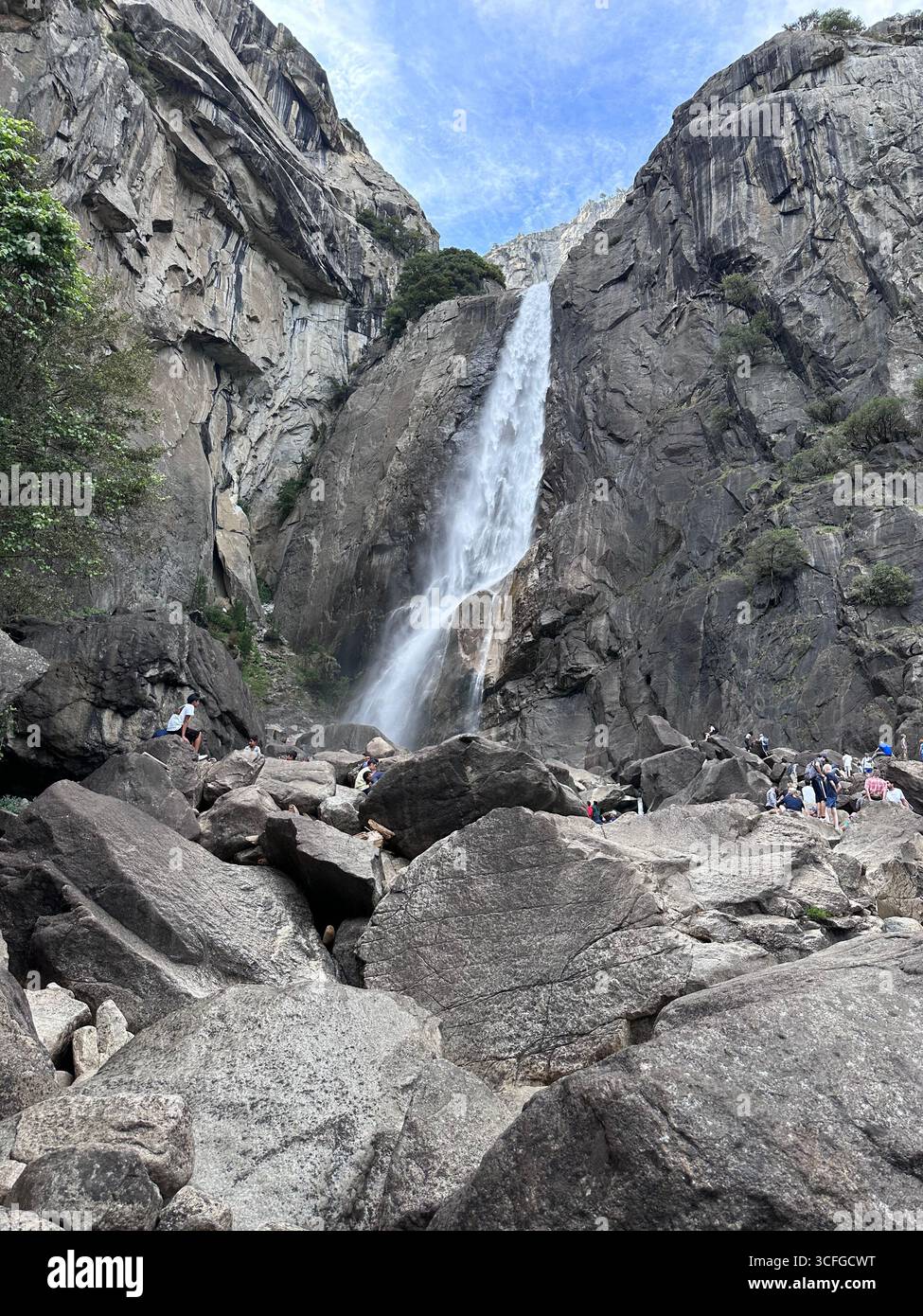 Les touristes admirent les Lower Falls de Yosemite qui descendent en cascade les falaises de granit, avec de grands rochers au premier plan dans le parc national de Yosemite, Californie, États-Unis - Image de stock capturée avec un smartphone