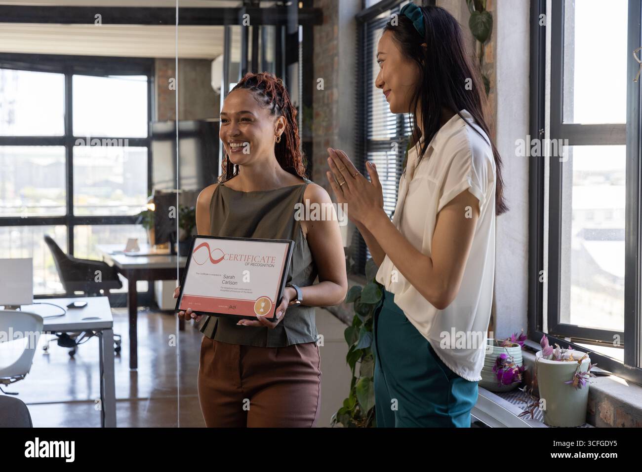 Diverses collègues féminines en tenue d'affaires détenant un certificat et applaudissant au bureau Banque D'Images