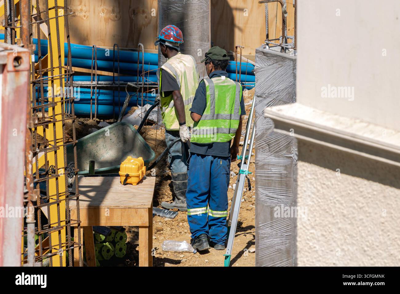 Deux ouvriers en uniforme et gilet réfléchissant sur un chantier de construction. Banque D'Images