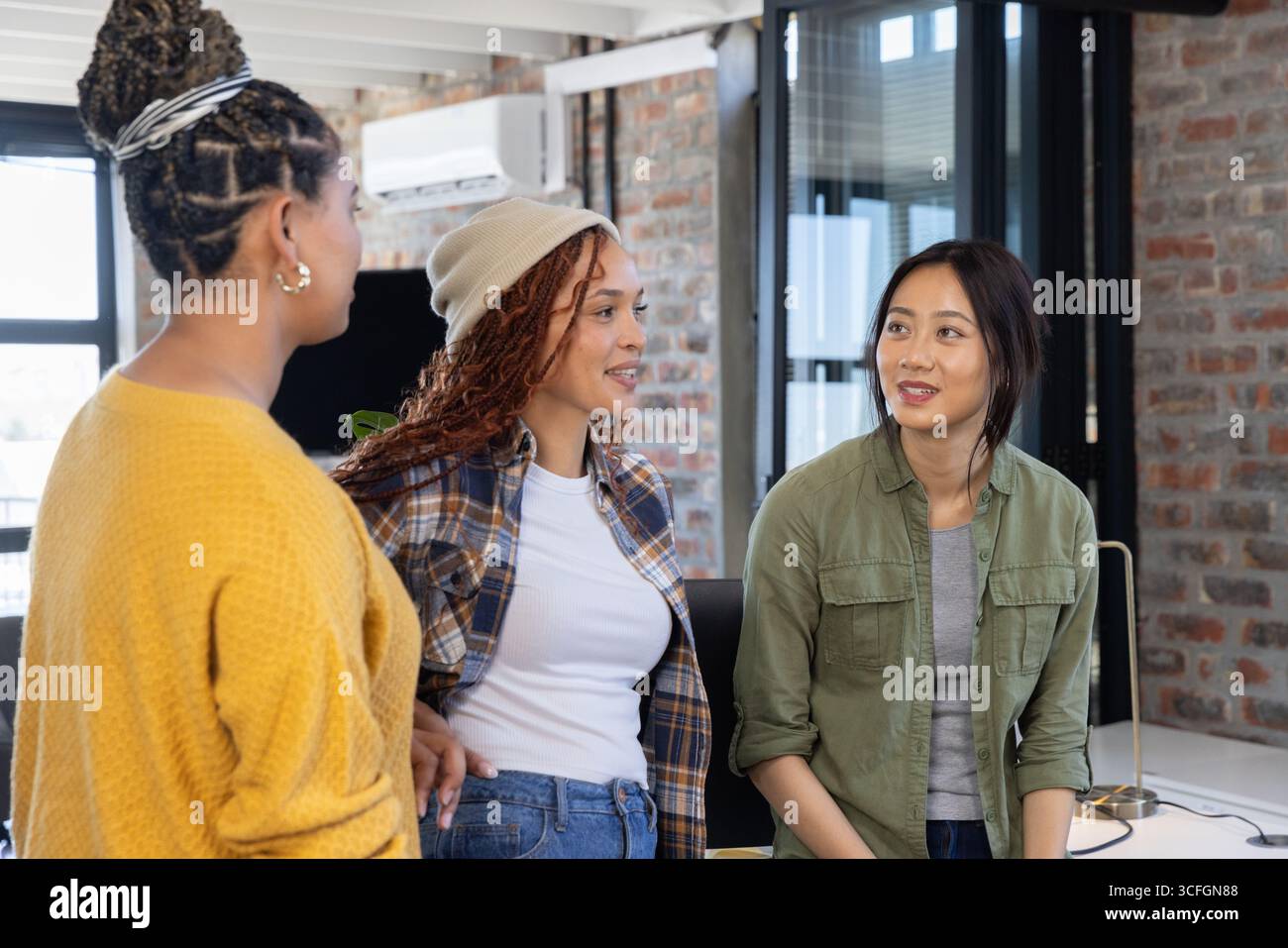 Diverses collègues féminines discutant des idées au bureau avec lampe et plante en pot dans le bureau ouvert Banque D'Images