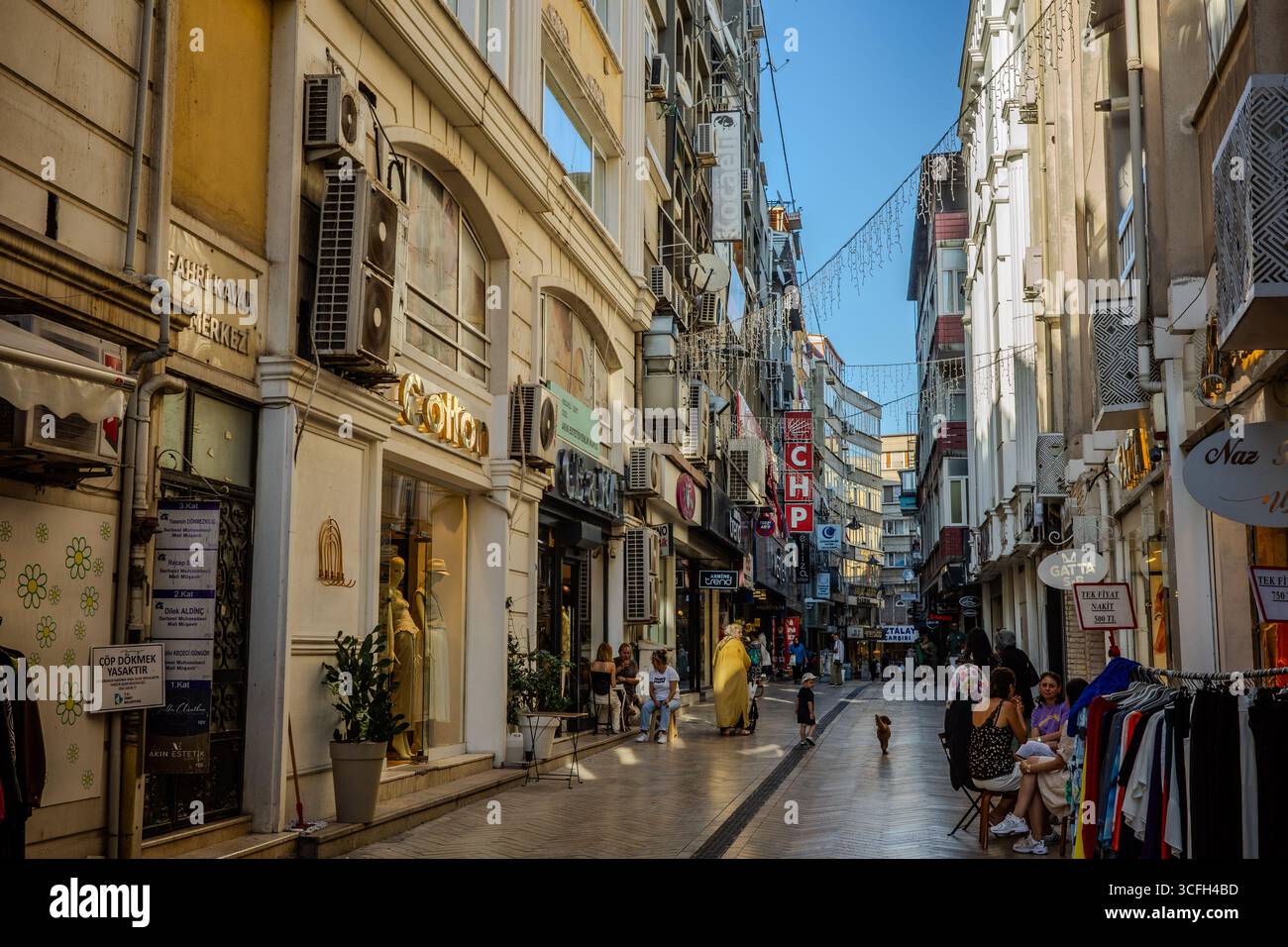 Rue piétonne avec des magasins de vêtements, des cafés, et des gens marchant et assis le long des devantures à Izmit, Kocaeli, Turkiye. Izmit, Kocaeli, Turkiye – A Banque D'Images