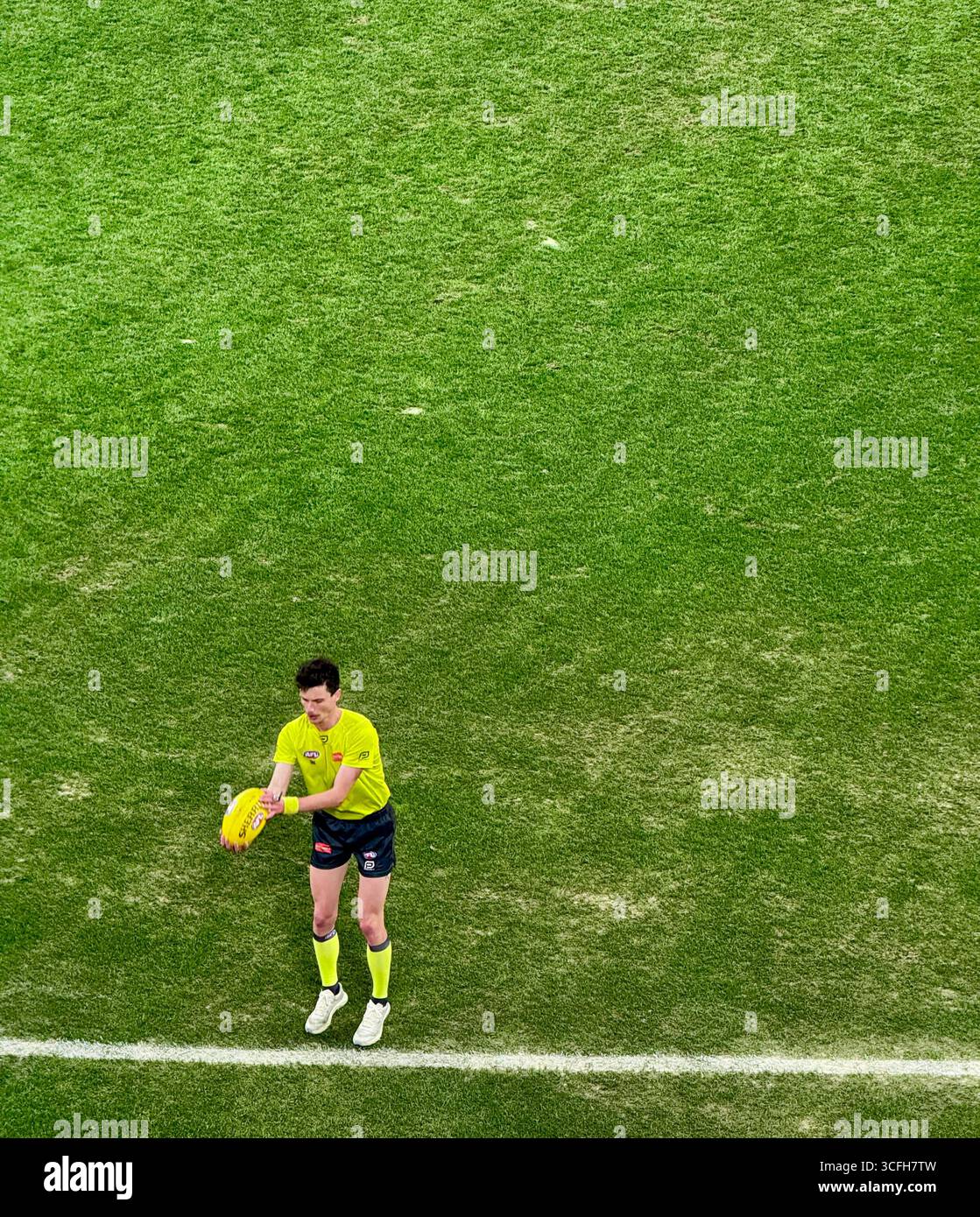Arbitre de frontière à un match AFL sur le point de lancer la balle en jeu. - Image de stock capturée avec un smartphone