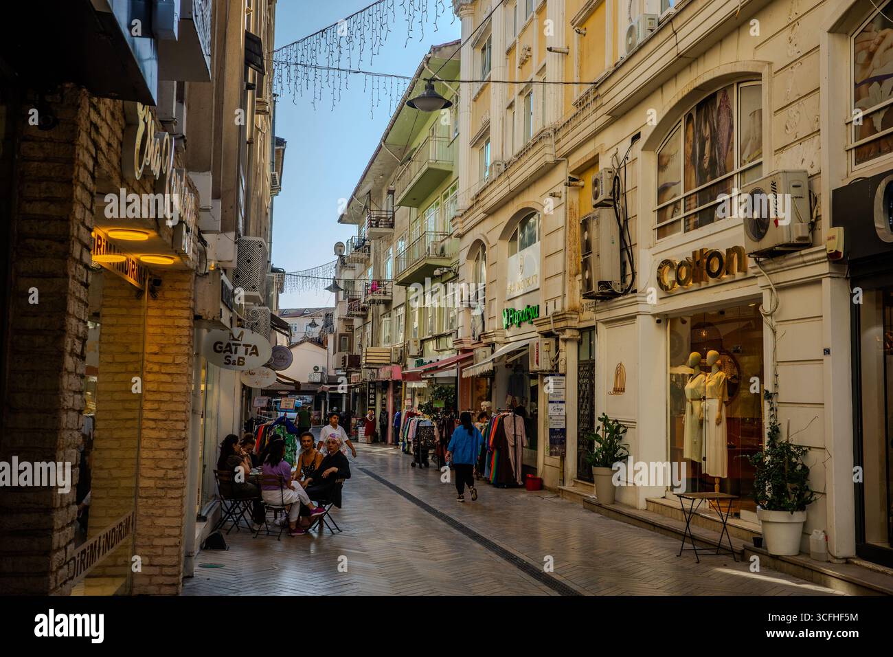 Rue commerçante piétonne avec des magasins de vêtements, des cafés et des gens marchant et assis à l'extérieur à Izmit, Kocaeli, Turkiye. Izmit, Kocaeli, Turkiye Banque D'Images