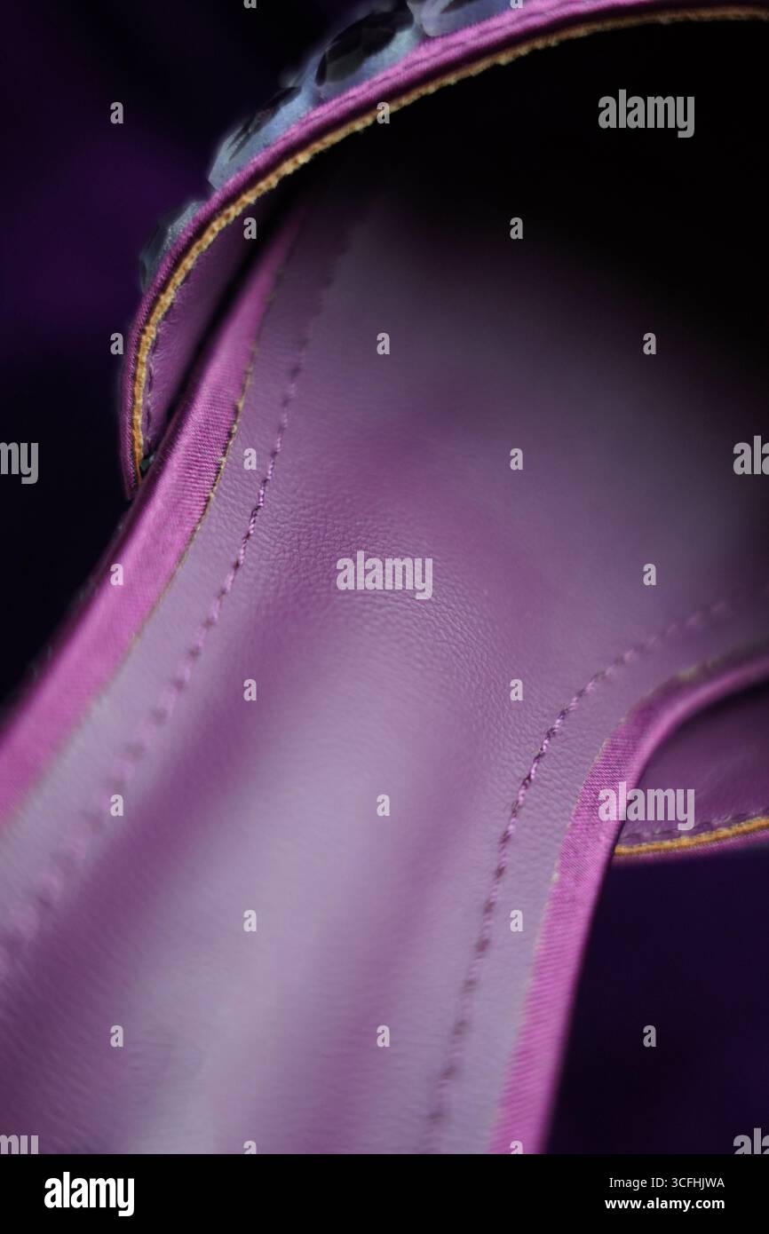 Un gros plan détaillé révèle la surface texturée du cuir violet, présentant de fines coutures et les variations subtiles de son ton. L'éclairage doux Banque D'Images