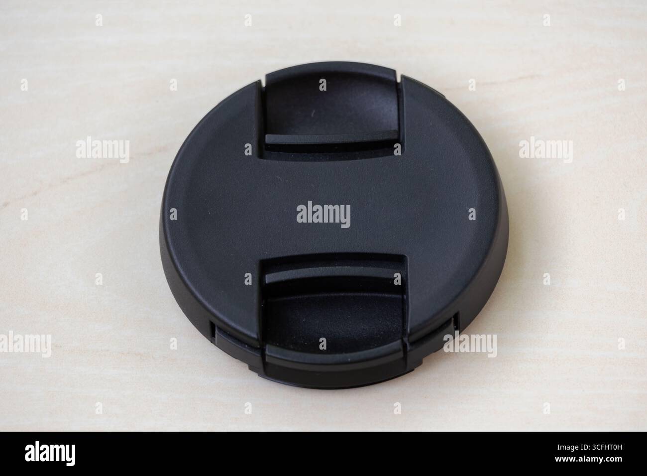 Vue rapprochée d'un capuchon d'objectif noir sans logo sur fond en bois. Un cache d'objectif ou un cache protège les objectifs de l'appareil photo des rayures, de la poussière et de la pluie Banque D'Images