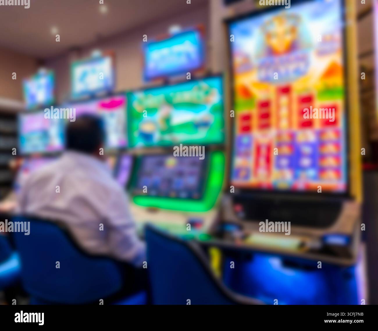 Homme jouant à la machine à sous à l'intérieur du hall de casino éclairé Banque D'Images