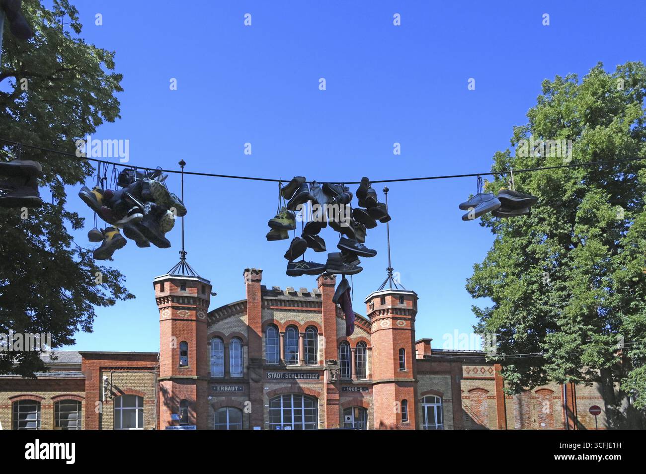 Chaussures suspendues en laisse, dans la cour d'une maison d'habitation pour toxicomanes, chaque chaussure est un rappel d'une personne décédée, derrière un ancien industriel Banque D'Images
