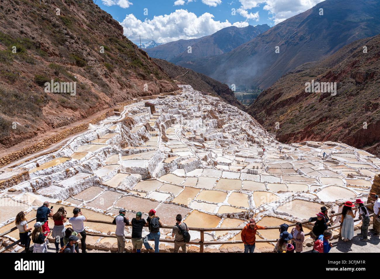 Touristes visitant les étangs salants de Maras à Cusco, Pérou. Attraction de la vallée sacrée avec piscines d'évaporation en terrasse, patrimoine culturel et vues panoramiques. Banque D'Images
