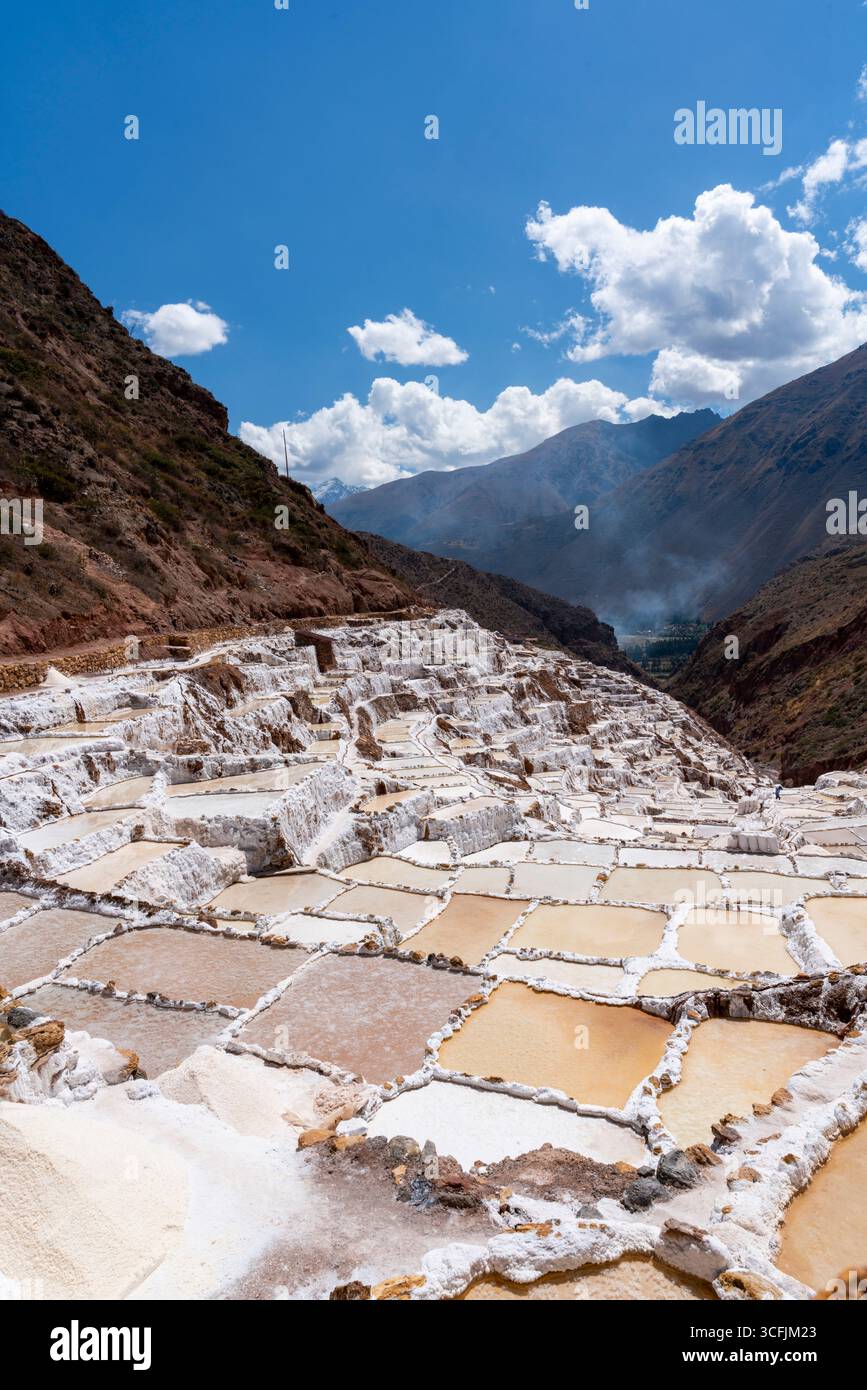 Maras marais salants à Cusco, Pérou. Vue rapprochée des bassins d'évaporation de sel en terrasse aux teintes dorées sous le ciel andin, site historique du patrimoine inca. Banque D'Images