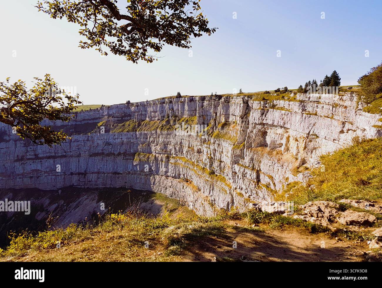 Paysage de parois rocheuses abruptes du creux du Van, connu sous le nom de « Grand Canyon » suisse, dans la lumière chaude du matin d'automne sous un ciel bleu Banque D'Images