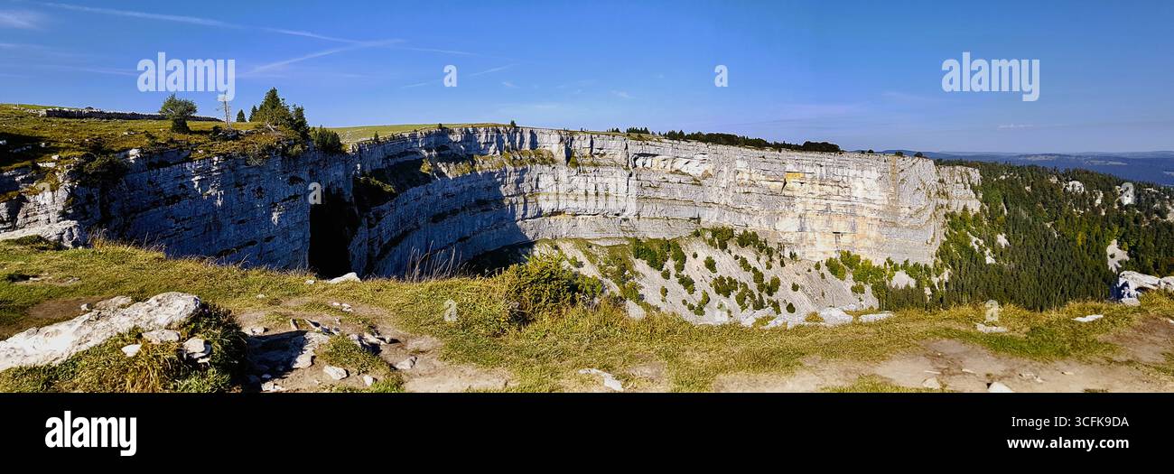 Panoramique des parois rocheuses escarpées du creux du Van, connu sous le nom de « Grand Canyon » suisse sous la lumière chaude du soleil matinal d'automne sous un ciel bleu, Suisse Banque D'Images