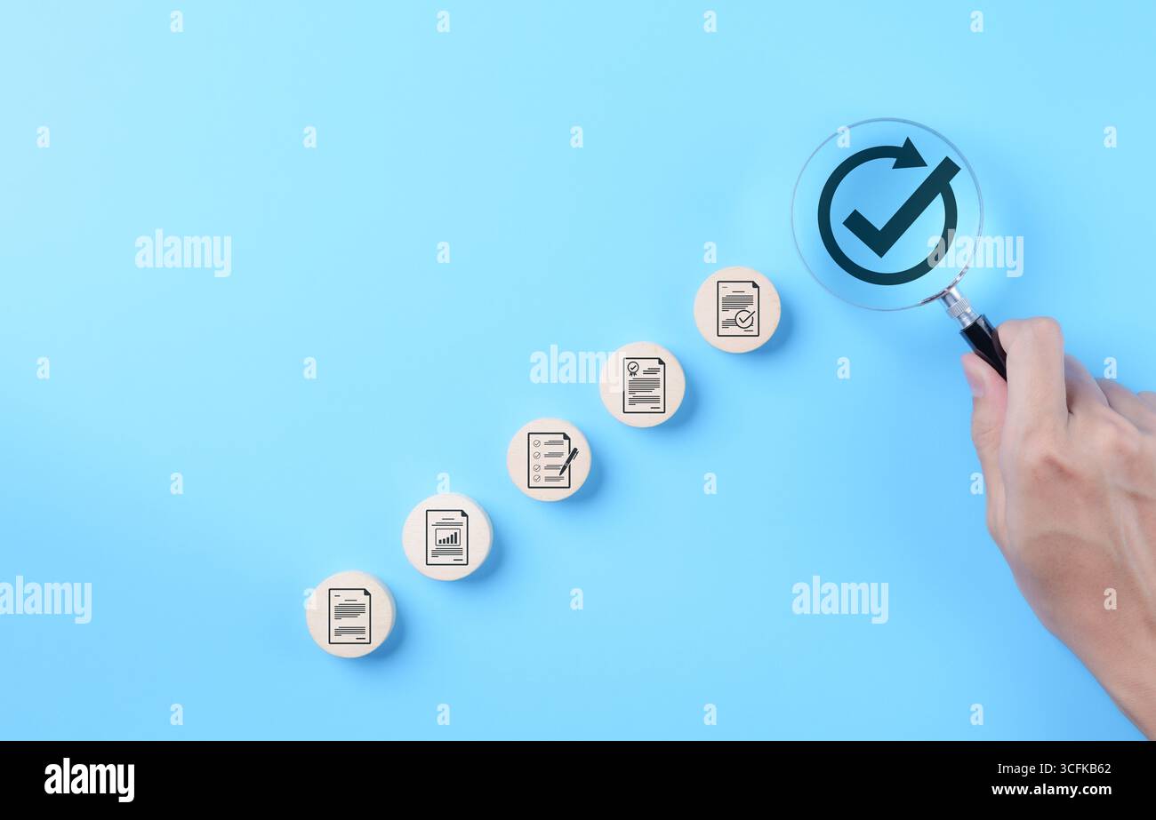 Documenter les concepts de processus d'approbation et d'assurance qualité. Main tenant une loupe en se concentrant sur le symbole de coche avec icône de document, document Banque D'Images
