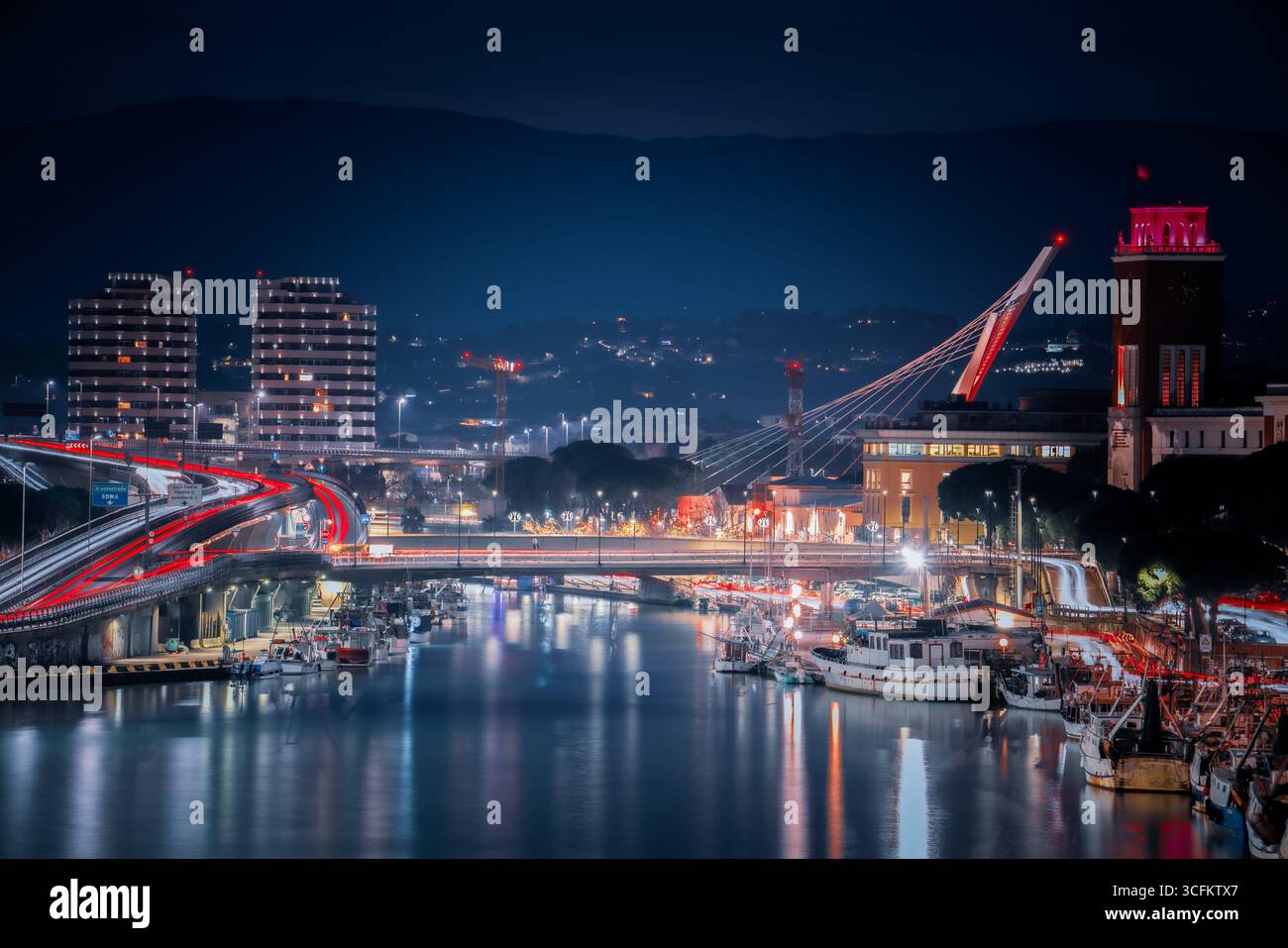 Vue nocturne de Pescara, Abruzzes, Italie, montrant le pont illuniné Ponte del Mare, la ligne d'horizon moderne, le front de mer Adriatique, et les reflets de la ville Banque D'Images