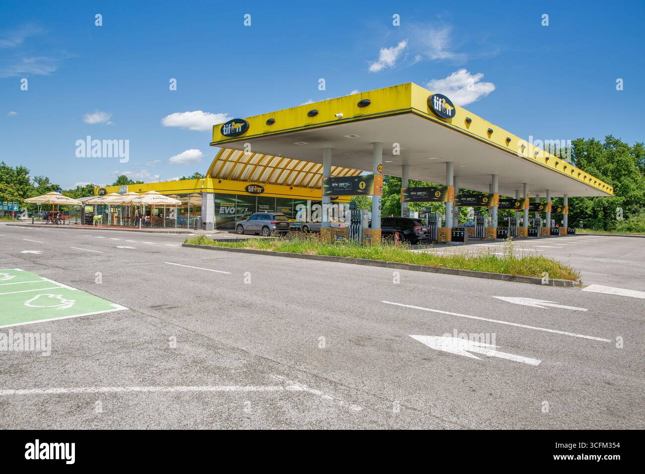 Draganic, Croatie - 31 mai 2025 : station-service contemporaine Tifon avec salle à manger extérieure avec parapluies de marque Jana, sculpture décorative de vache, Banque D'Images