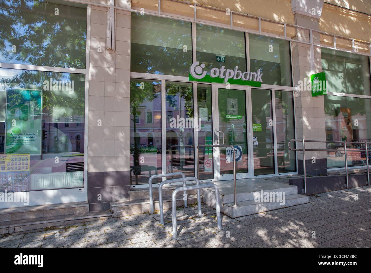 Nagykanizsa, Hongrie - 18 mai 2025 : succursale contemporaine de OTP Bank avec de grandes fenêtres en verre, une marque verte et des supports à vélos en métal sur urb Banque D'Images