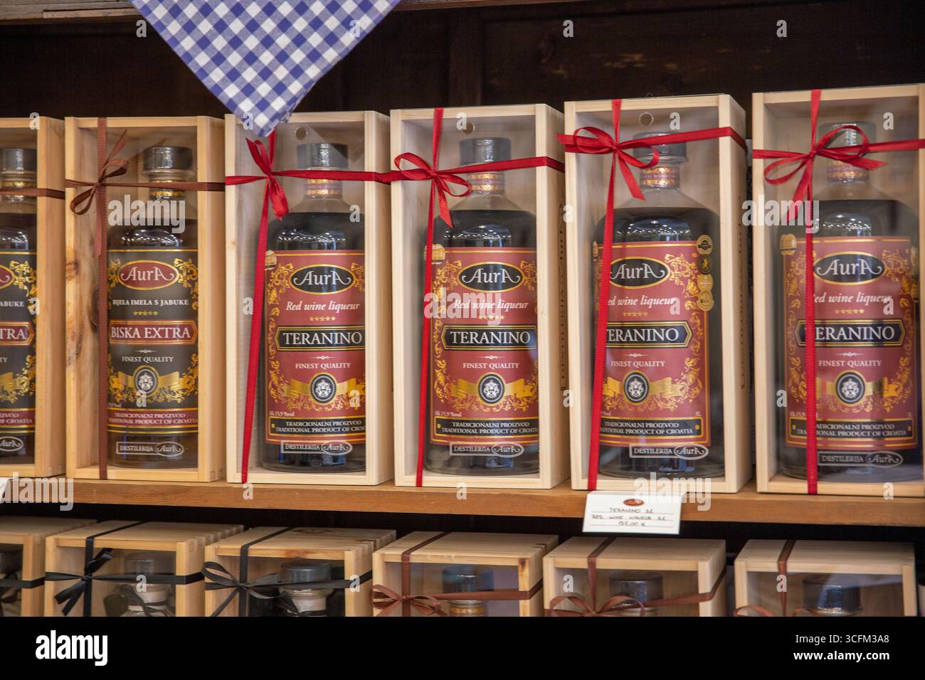 Novigrad, Croatie - 22 mai 2025 : bouteilles de liqueur de vin rouge aura Teranino avec des étiquettes traditionnelles sur l'étagère en gros plan dans une distillerie locale. Artisan Croatie Banque D'Images