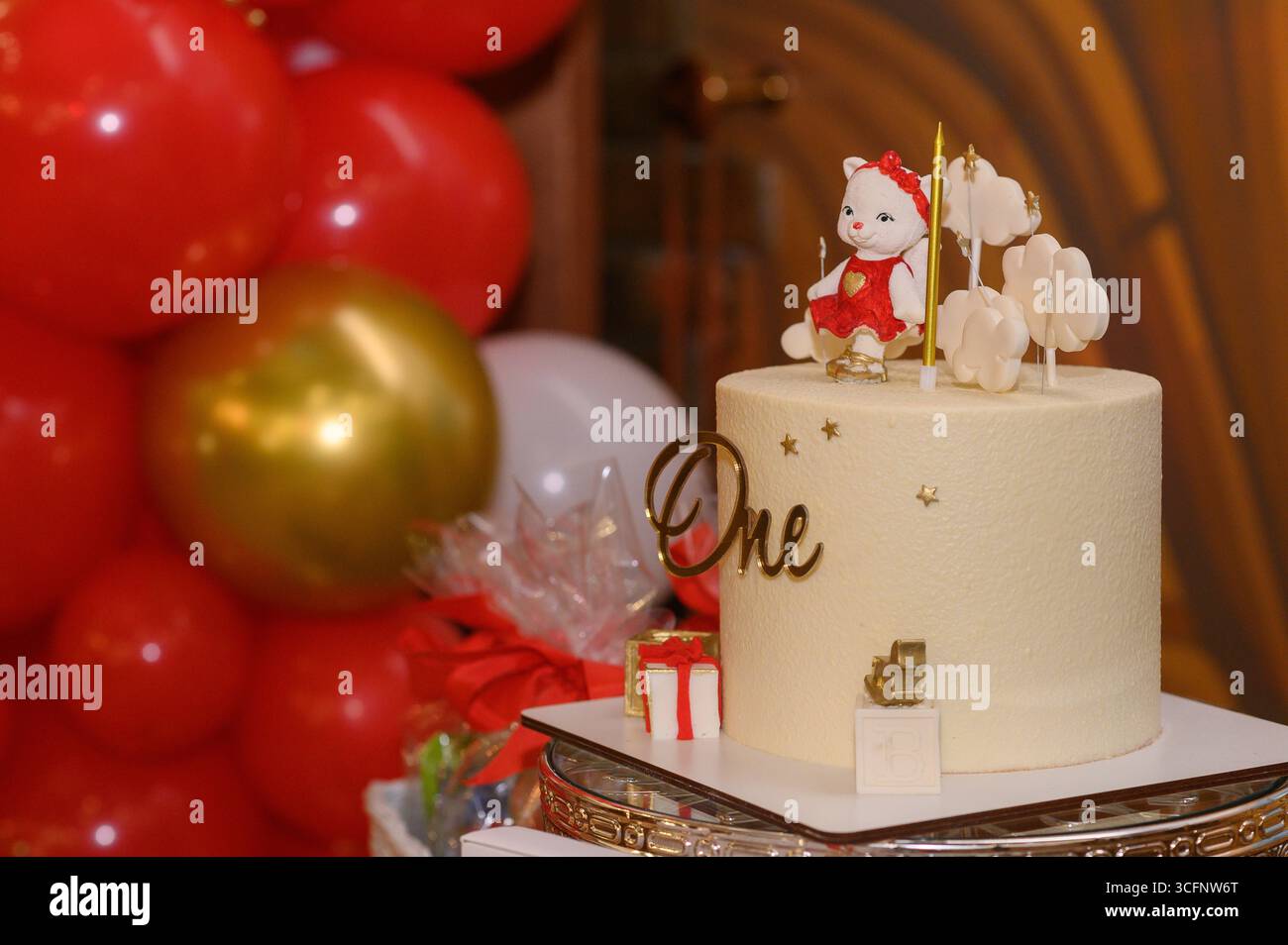 Gâteau d'anniversaire d'un an avec figurines animales, entouré de ballons dorés et rouges. ambiance festive et joyeuse parfaite pour célébrer les enfants. un Banque D'Images