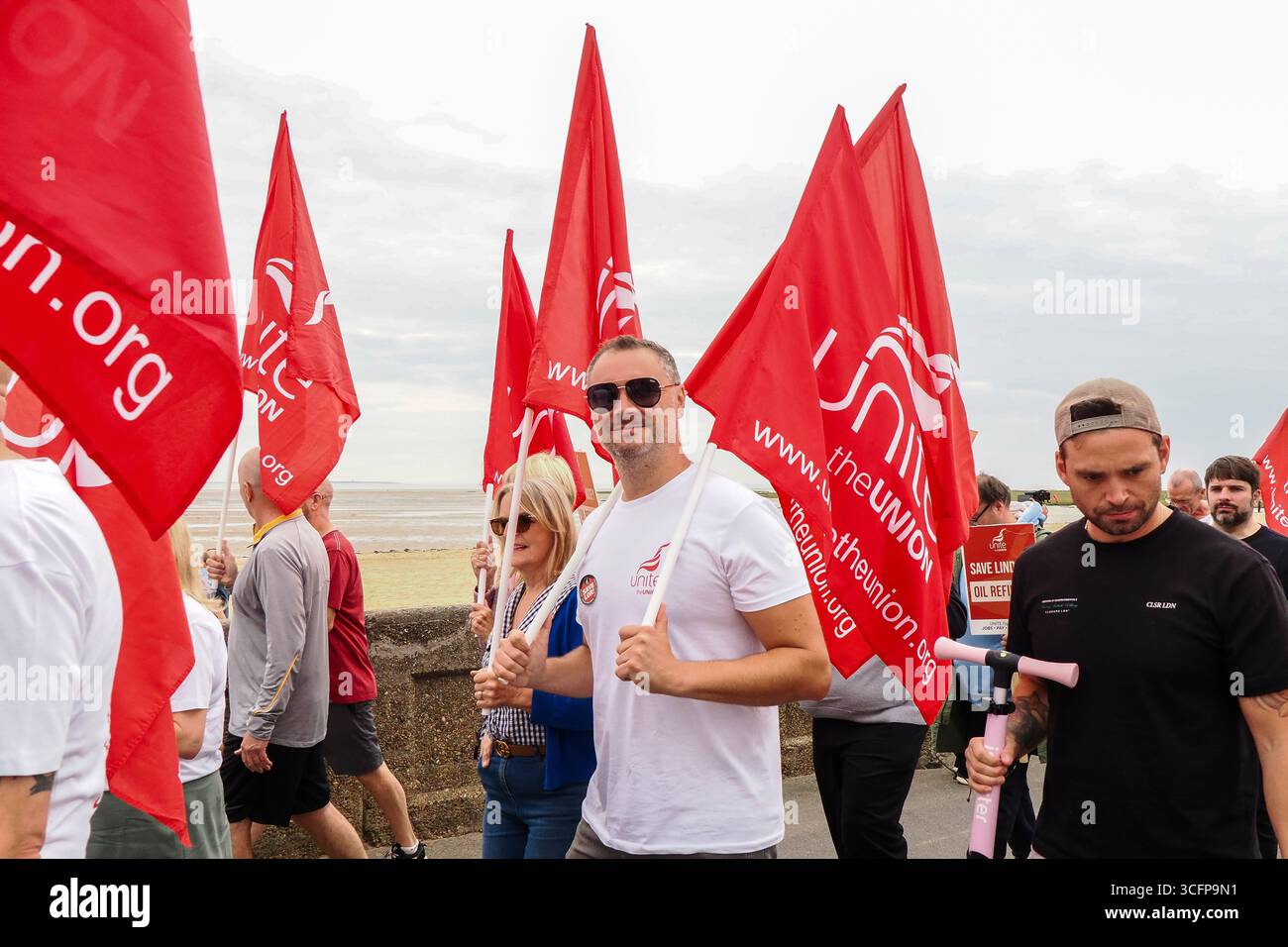 Cleethorpes, Royaume-Uni . 24 août 2025. De gauche à droite, les manifestants défilent vers l'avant en brandissant des drapeaux pendant le rassemblement de protestation de Save Lindsey Oil Refinery – manifestation Cleethorpes contre la fermeture de Central Promenade. Crédit : Freddie Yeo/Alamy Live News Banque D'Images