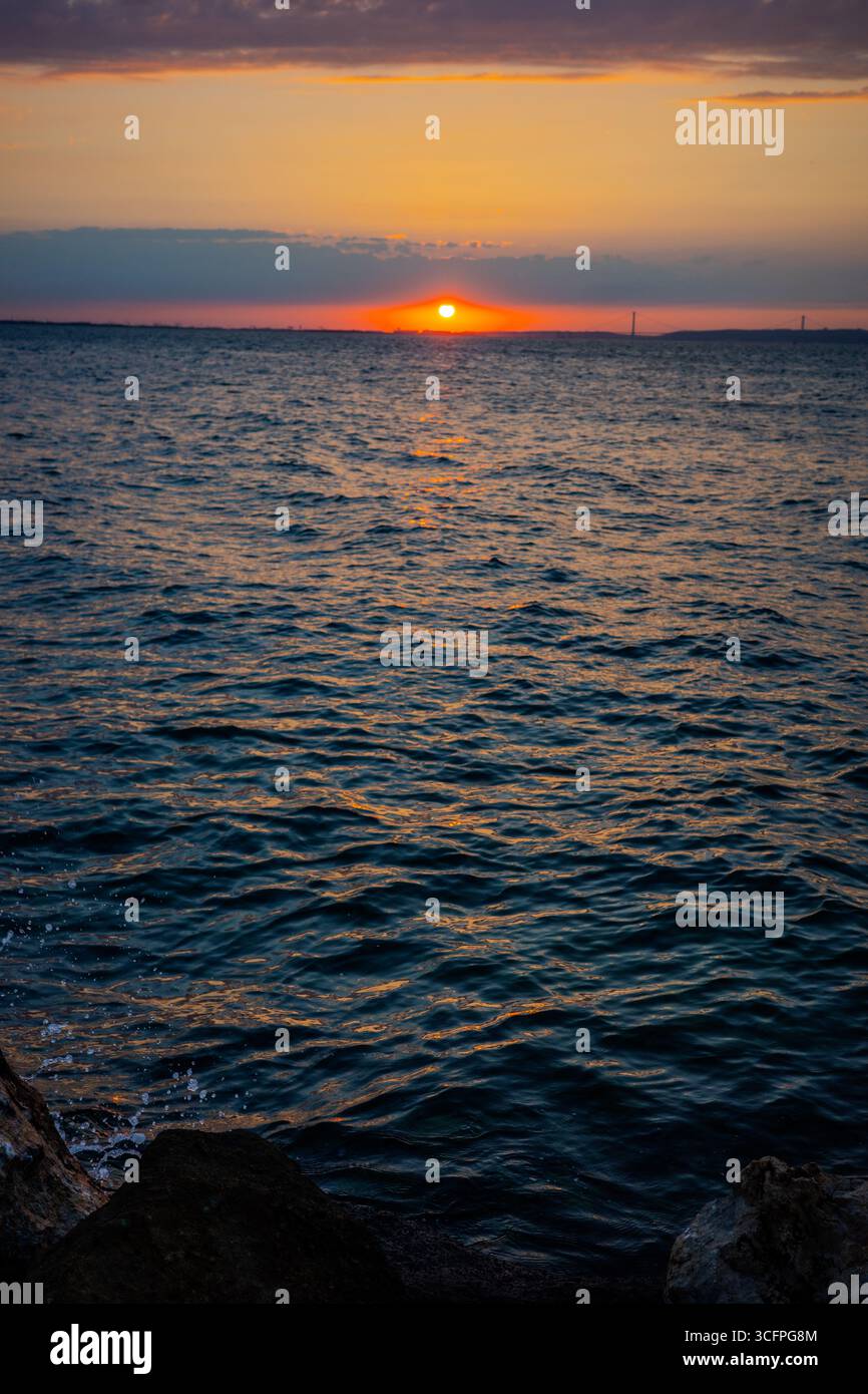 Le soleil se couche sur la mer de Marmara à Karamürsel, Kocaeli, Türkiye, projetant des reflets dorés sur l'eau ondulée. Karamürsel, Kocaeli, Türkiye Banque D'Images
