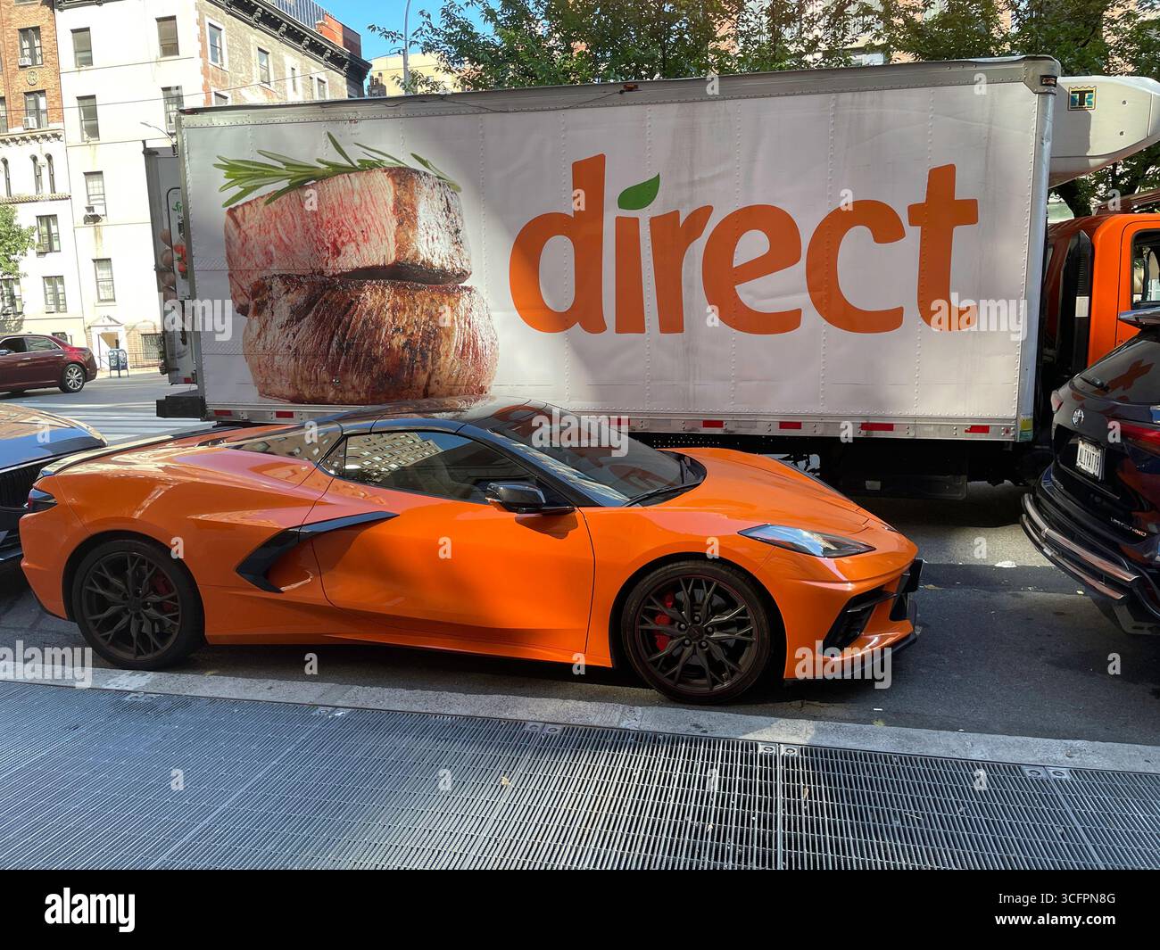 Scène de rue humoristique d'une Corvette super rapide garée à côté d'un énorme camion direct frais à Midtown Manhattan, 2025, New York City, États-Unis Banque D'Images