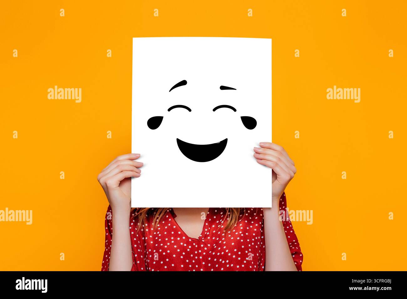 Fille tenant une affiche en papier avec un sourire heureux isolé sur fond orange. Concept humour Banque D'Images