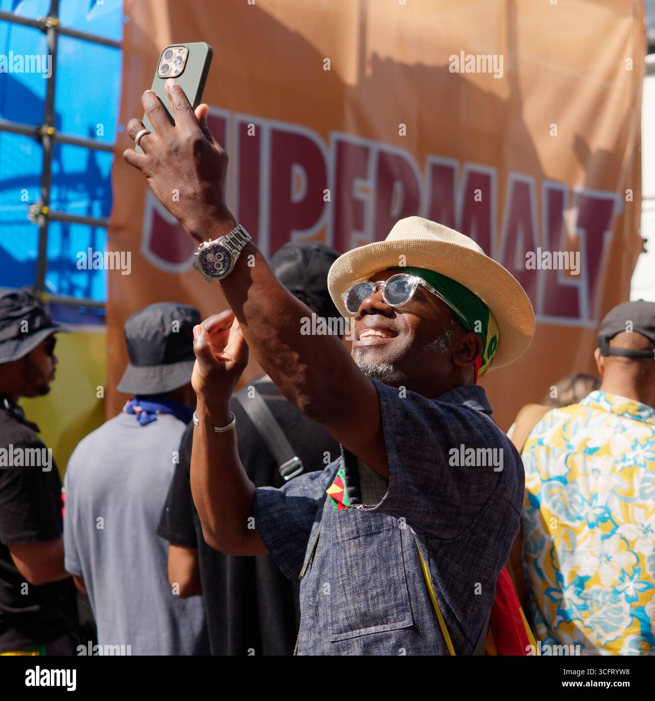 Homme avec chapeau et lunettes de soleil sourit comme il fait un selfie Notting Hill Carnival, Londres. Angleterre 25 août 2025 Banque D'Images