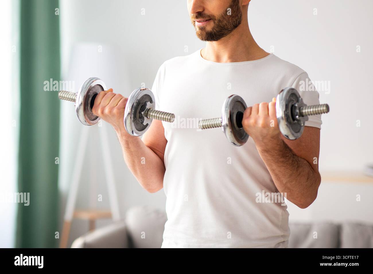 Gros plan de beau barbu homme faisant l'entraînement de haltères à la maison Banque D'Images