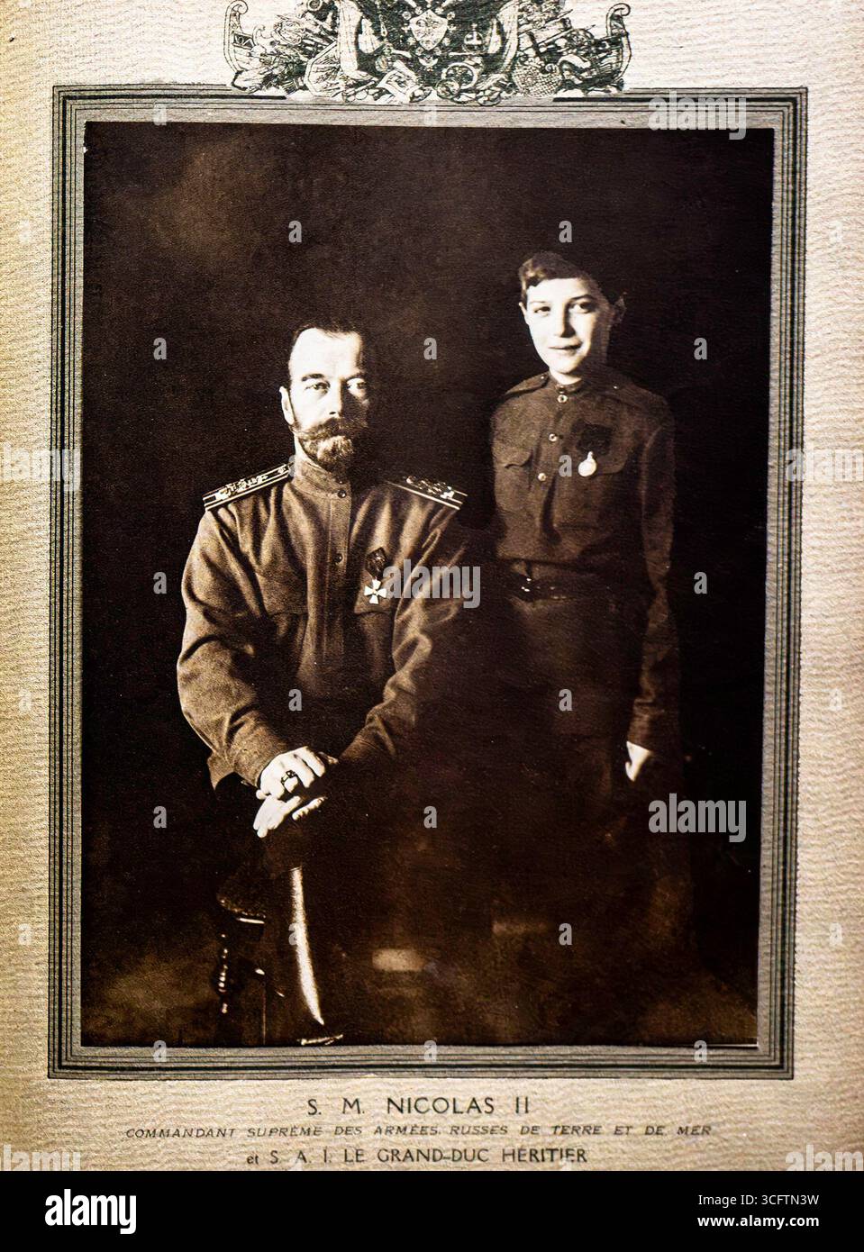 Photographie du tsar Nicolas II de Russie avec son fils, Tsarevich Alexei Nikolaevich, héritier du trône russe. Publié pendant la première Guerre mondiale, le portrait montre Nicolas II en uniforme militaire en tant que commandant suprême de l’armée et de la marine russes, aux côtés du jeune héritier portant un uniforme de cadet avec des médailles. L’image reflète à la fois la tradition dynastique et le rôle symbolique de la famille impériale dans la Russie en temps de guerre, peu avant l’effondrement de la dynastie Romanov. Banque D'Images