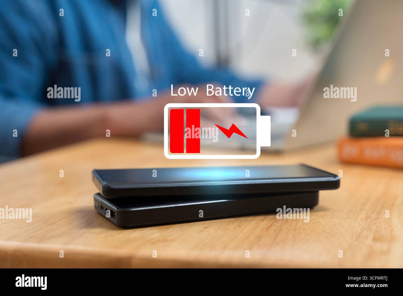 Smartphone avec icône d'avertissement de batterie faible sur l'écran et banque de puissance sur la table en bois, symbolisant l'énergie, la technologie, la charge, l'électricité, déviateur mobile Banque D'Images