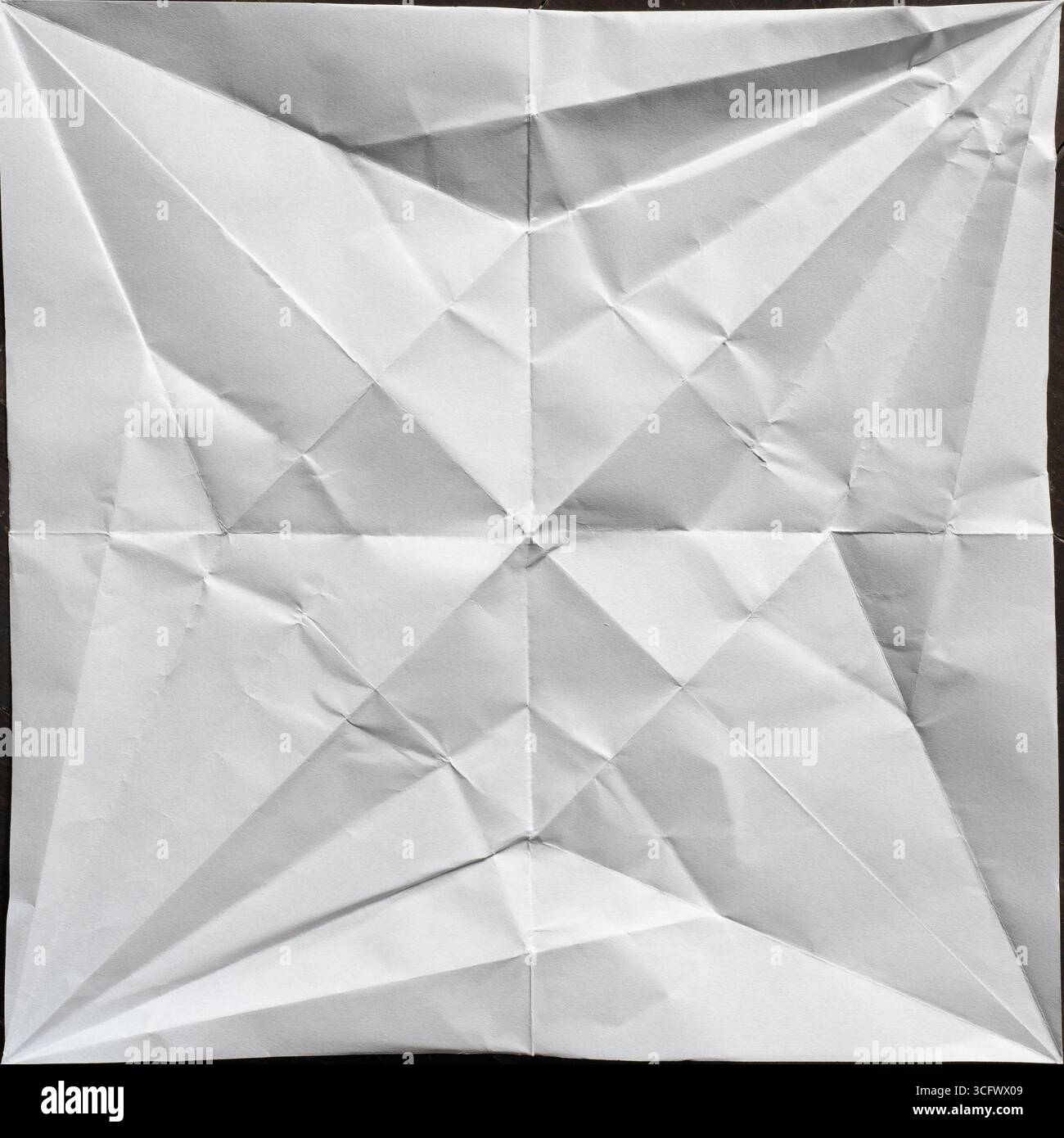 Grue Origami dépliée création d'une forme d'étoile noire et blanche symétrique abstraite sur papier carré Banque D'Images