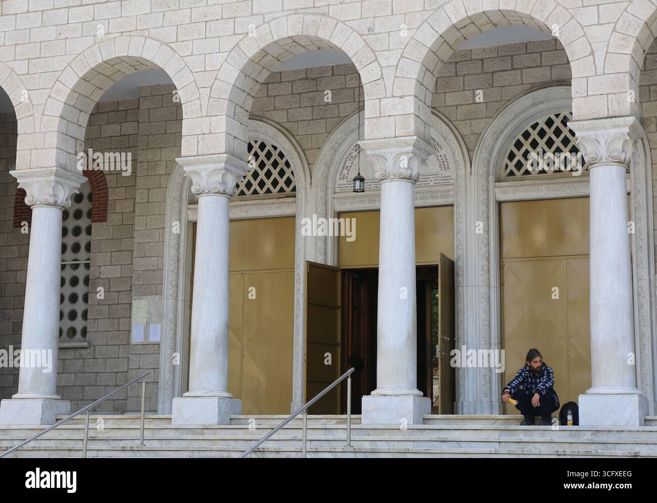Thessalonique, Grèce-23 avril 2025 : homme non identifié aux cheveux longs vendant des bougies entre les arches et les colonnes de l'église Panagia Deksia Banque D'Images
