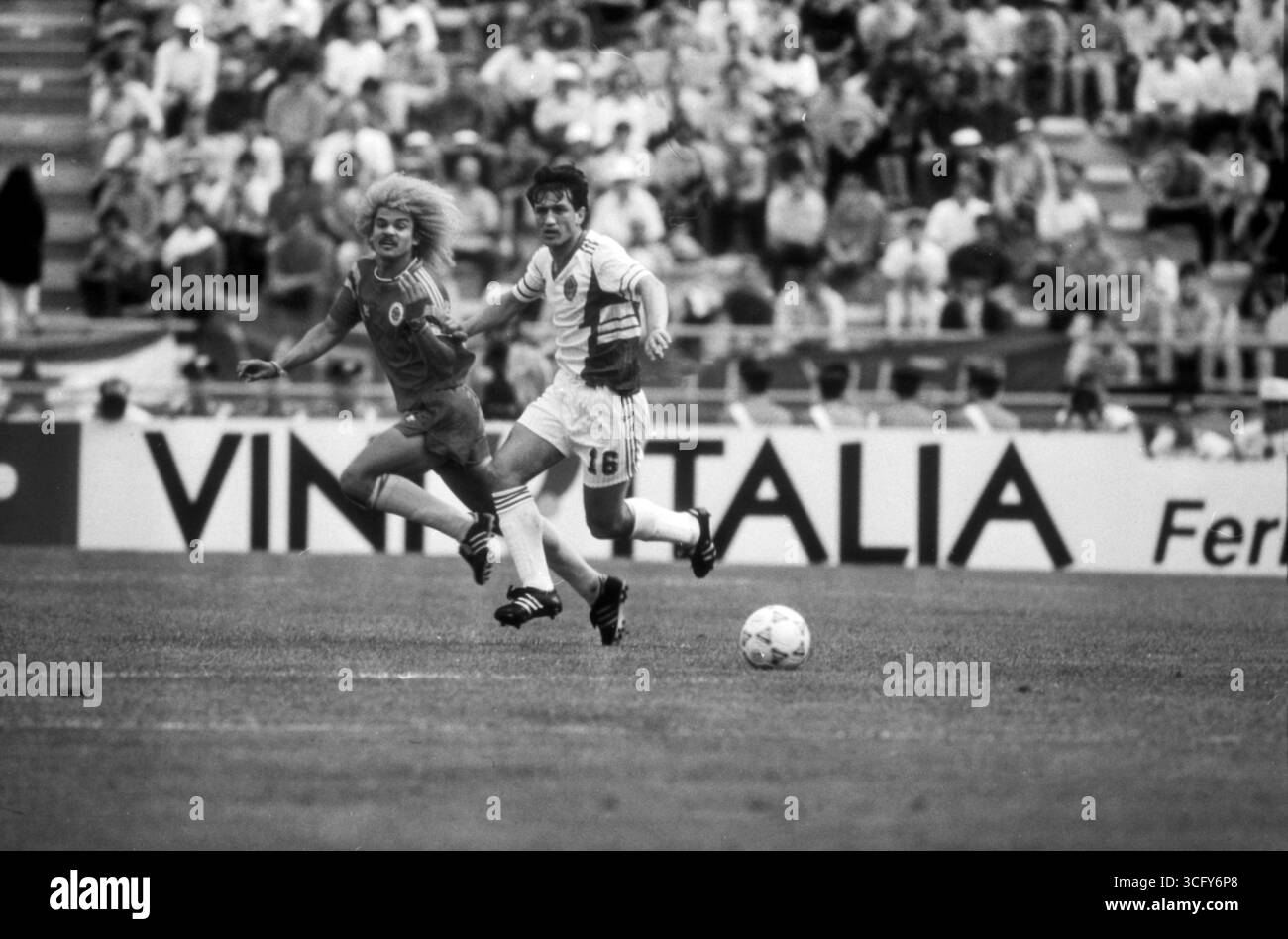 Refik Sabanadzovic (Jugoslawien) im Laufduell mit Carlos Valderrama (Kolumbien) während des Vorrundenspiels BEI der Fußball-WM 1990 in Italien. Banque D'Images