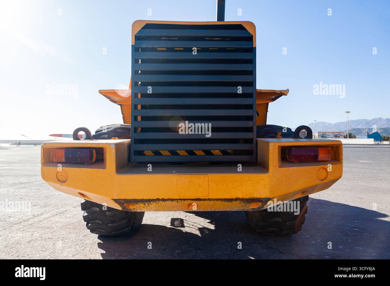 Un tracteur jaune lourd se tient sur l'asphalte dans la zone bâbord, vue de face. Banque D'Images